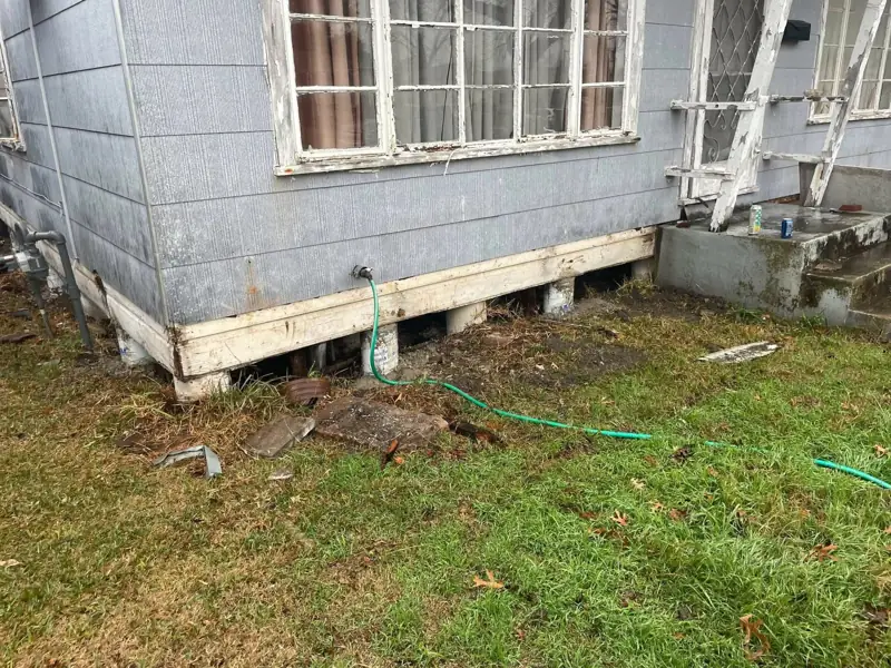 Completed repair along the base of a raised house with new trim board covering the rebuilt sill