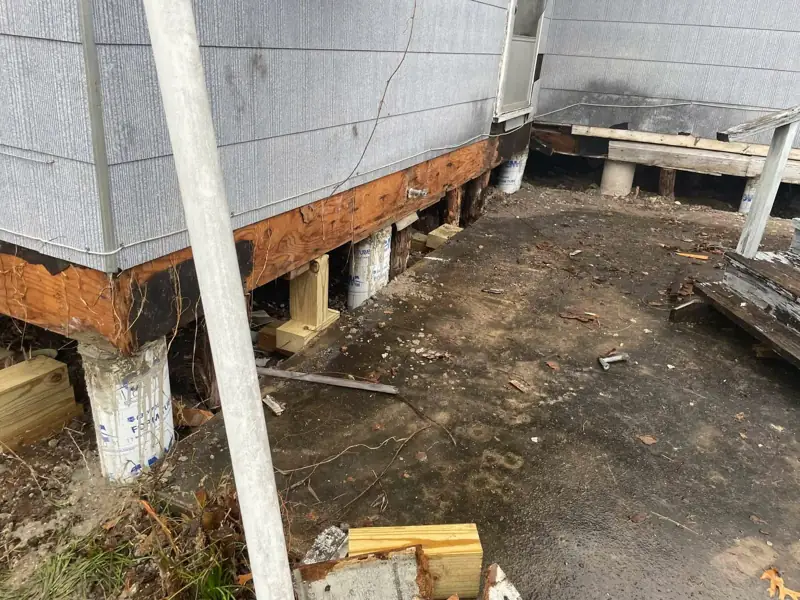 New treated wood sill beam resting on round concrete piers along the base of a raised house
