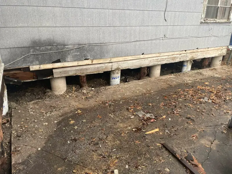 Fresh lumber sill plate and a row of concrete piers installed under the edge of a raised house