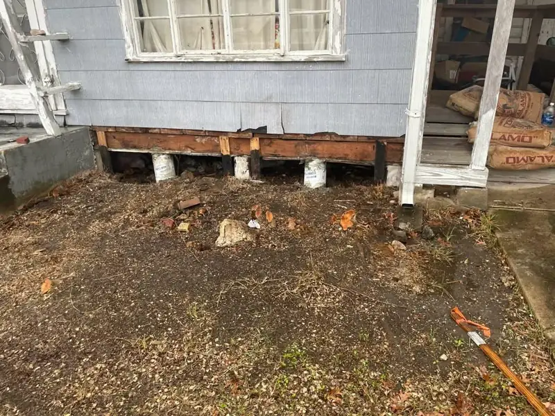 Perimeter beam of a raised house exposed during repair, with new concrete pier supports below